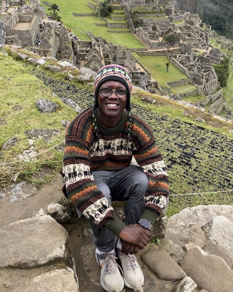 Zach smiling at Machu Picchu in a knit llama sweater and hat