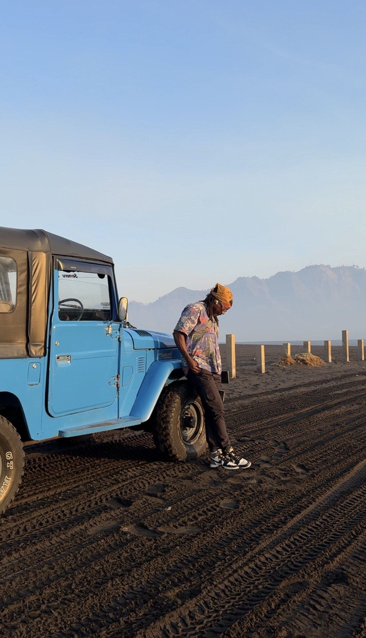 Zach leaning on a blue jeep in the volcanic sand sea at Bromo, East Java, just after sunrise